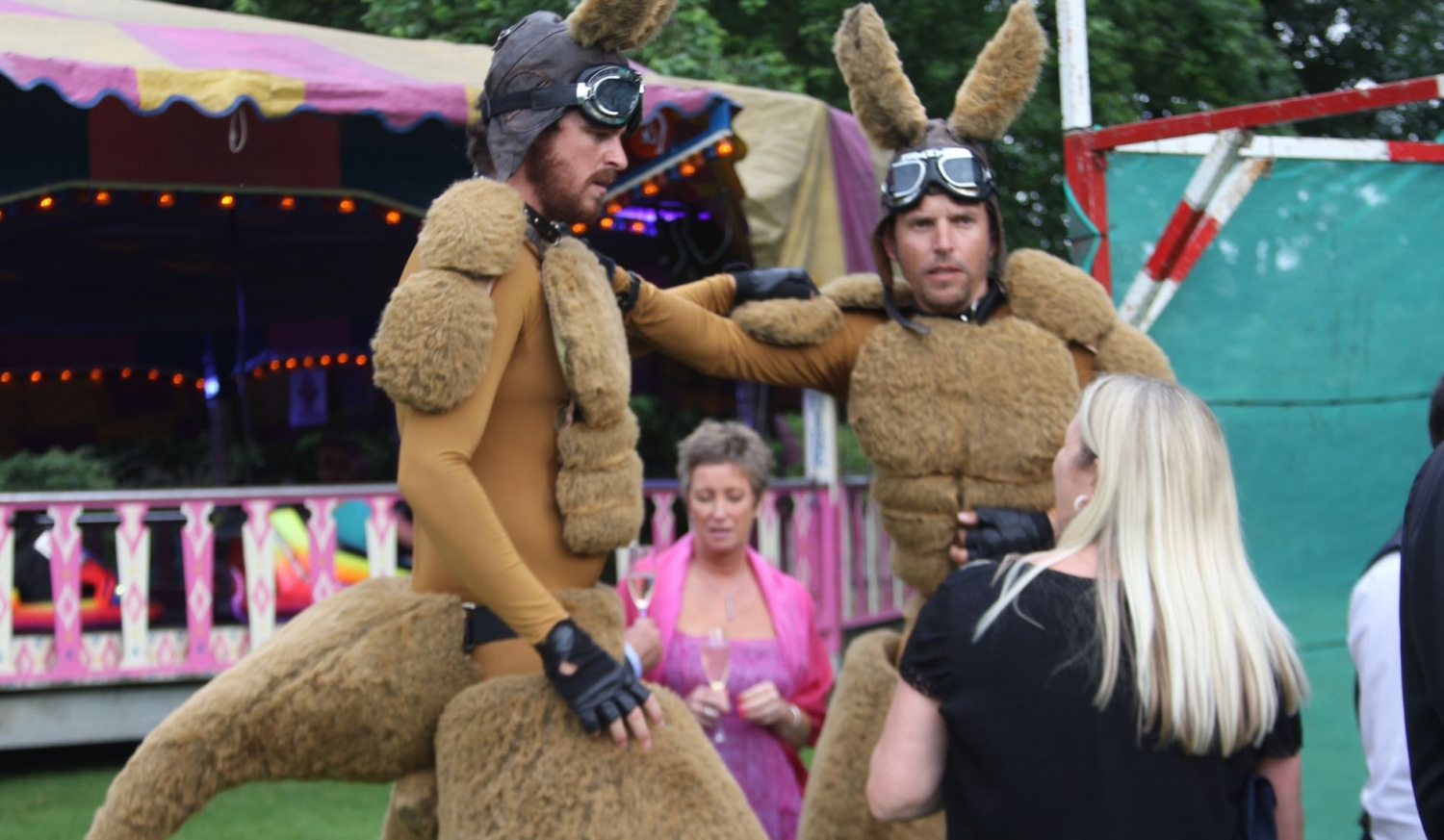 Image of a lady talking to giant Kangaroos with Dodgems in the background.