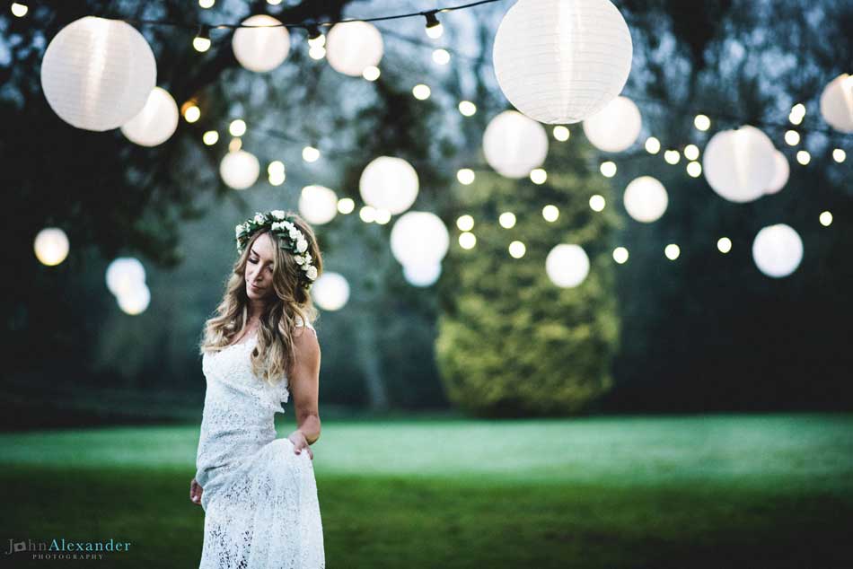 Image of a bride standing under white lights on a tree.