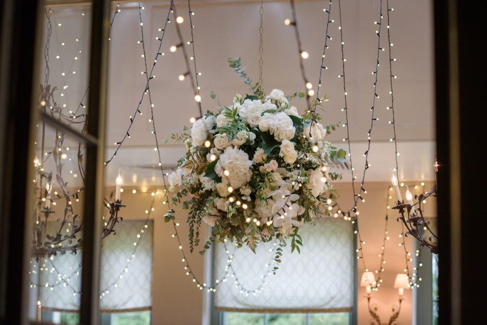 Image of a big ball of flowers with fairy lights in a dining room.