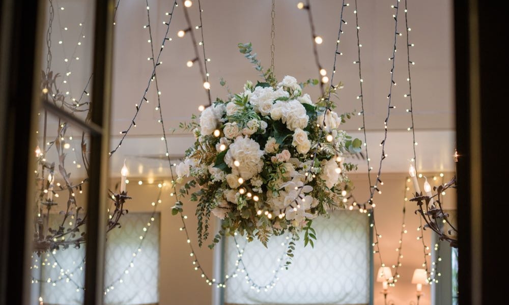 Image of a big ball of flowers with fairy lights in a dining room.