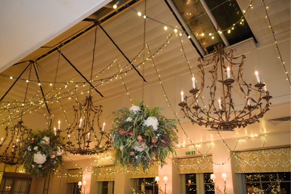 The Orangery at Babington House dressed for a wedding with 2 large flower balls and a fairy-light canopy.